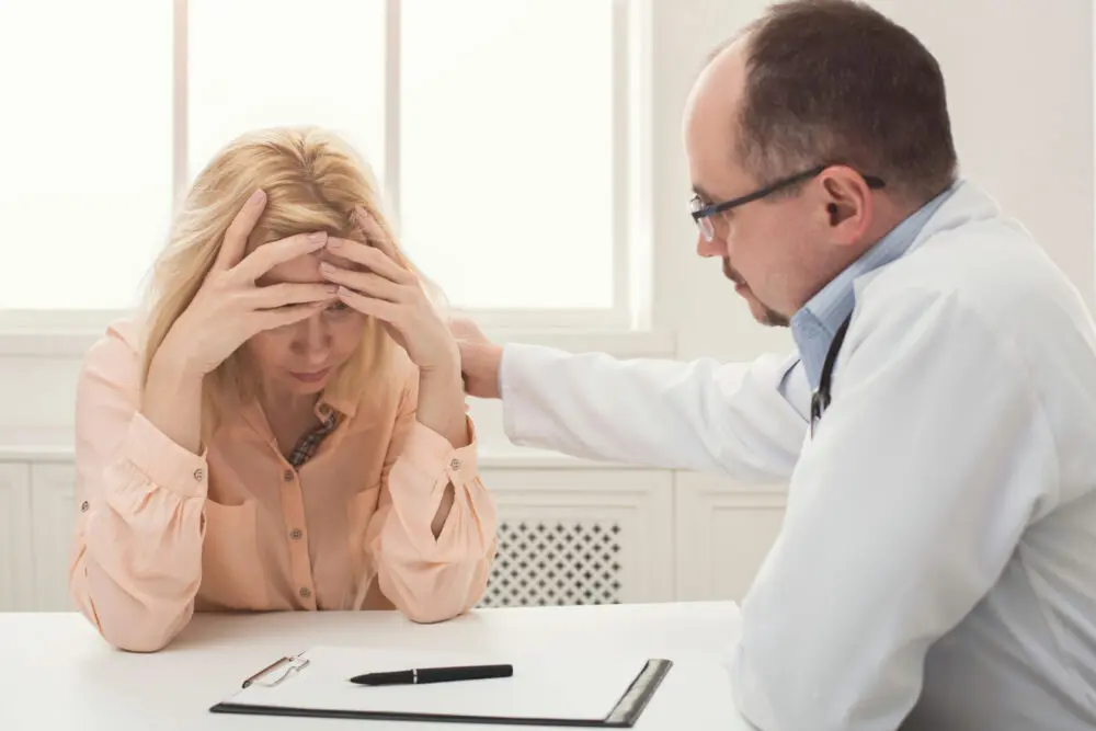 Woman showing emotional distress during discussion with doctor illustrating stages of relapse in recovery